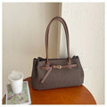 Front angle view of dark taupe brown woven shoulder tote bag with tan handles and buckle detail
