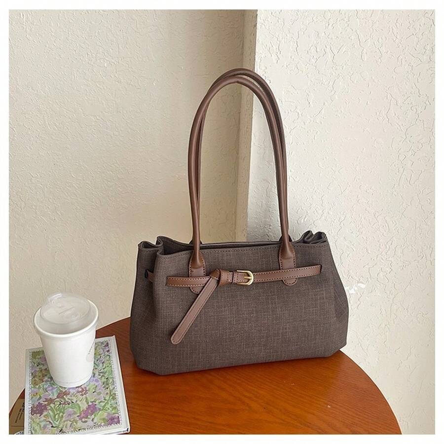 Front angle view of dark taupe brown woven shoulder tote bag with tan handles and buckle detail