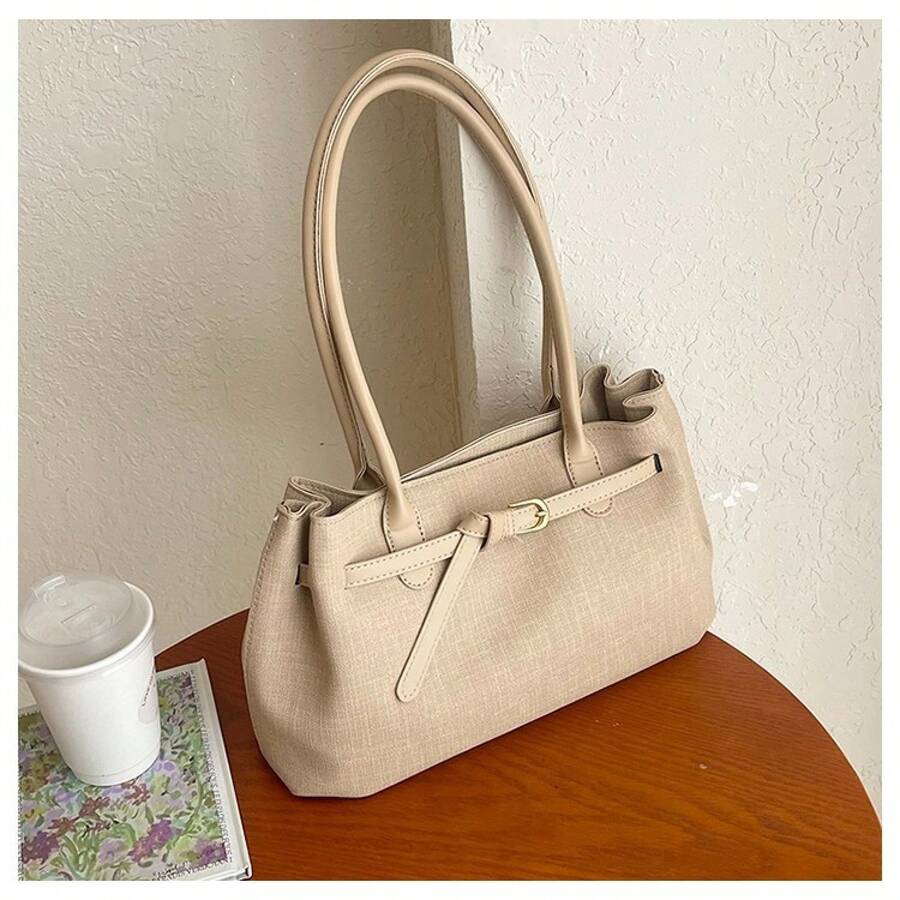 Front angle view of beige woven shoulder tote bag with double handles and gold buckle strap