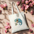 Angled flat lay view of white chameleon canvas tote bag with long straps and flowers