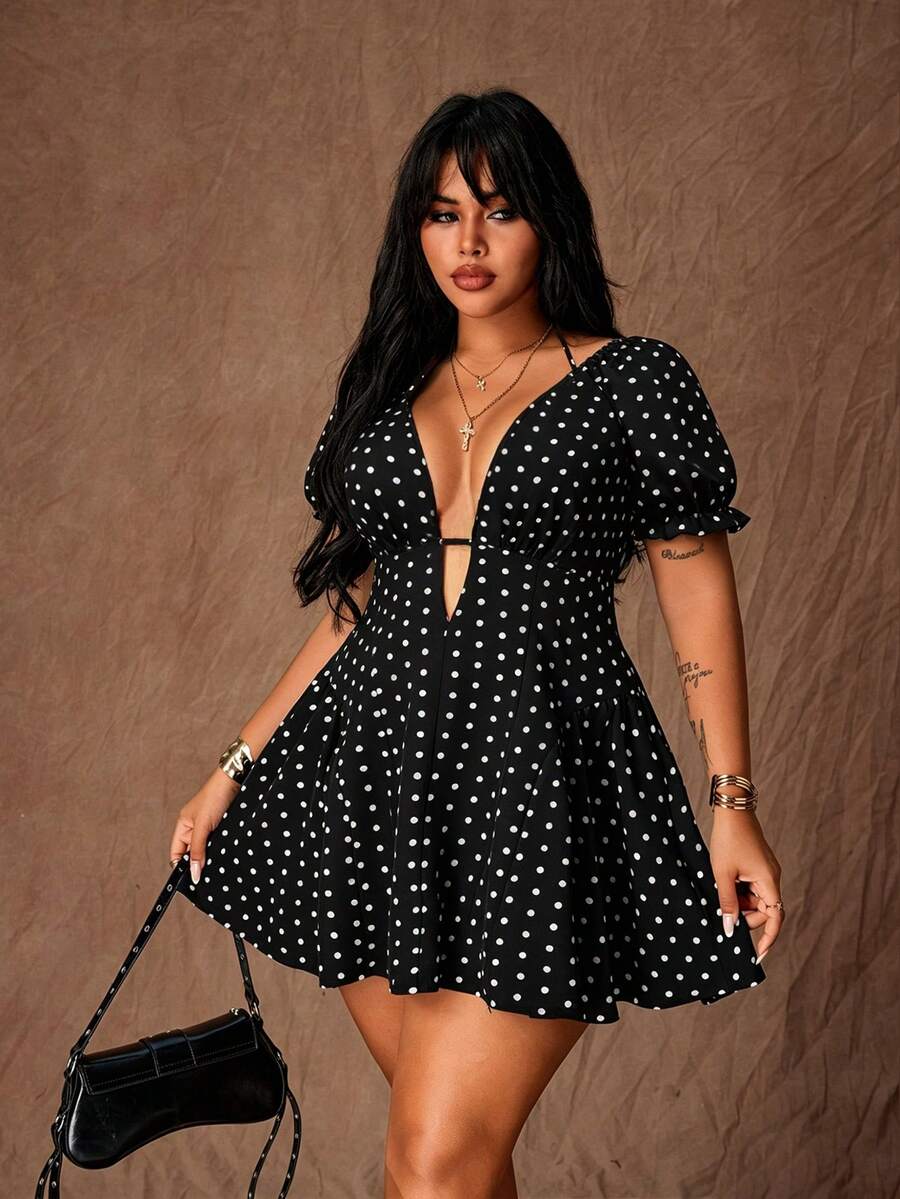 Front view of black dress with white polka dots, deep V-neck, short puff sleeves and flared skirt