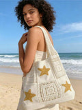 Shoulder worn beach view of cream crochet tote bag with yellow stars and open mesh