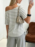 Back worn view of grey and white striped loose T-shirt styled off one shoulder