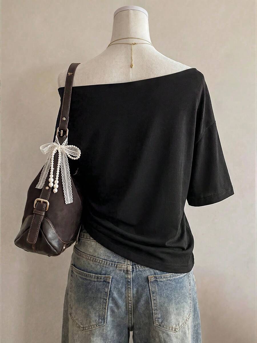 Back styled view of plain black off-shoulder T-shirt with loose elbow-length sleeves