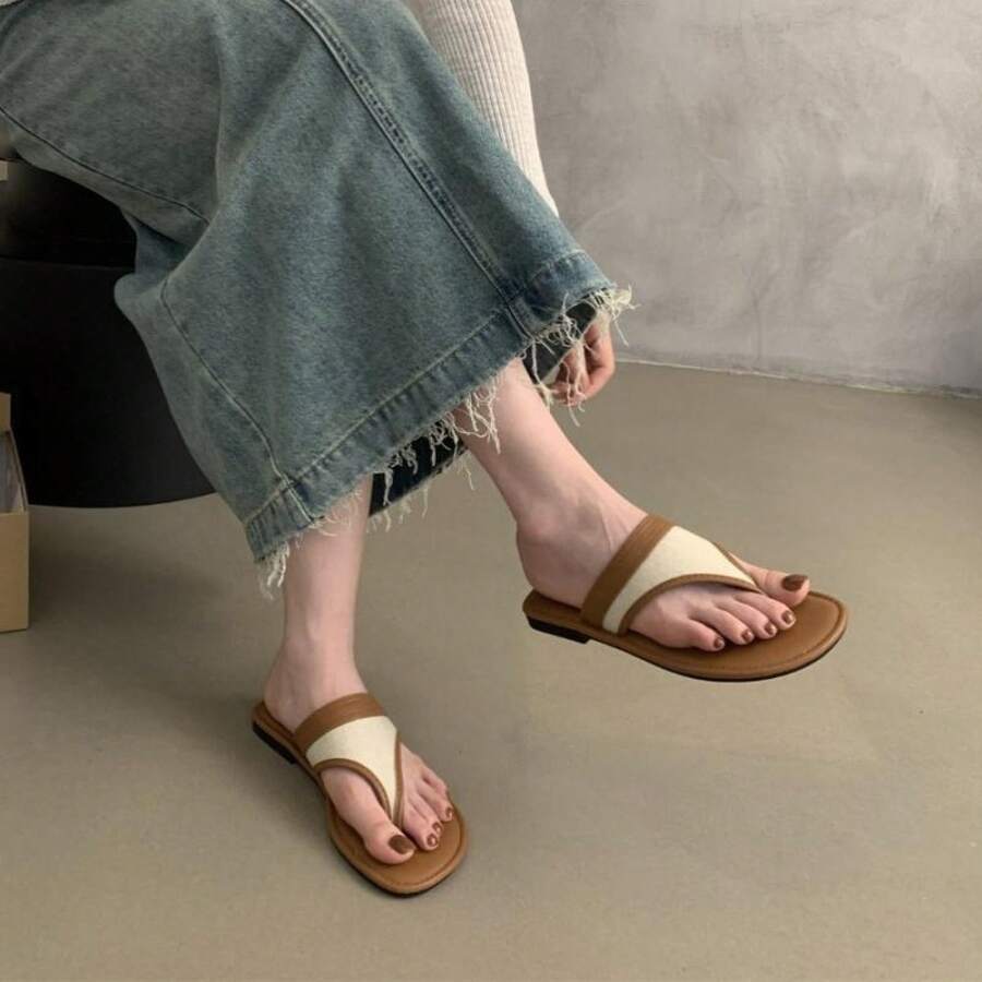 Worn view of two-tone brown and cream flat thong slide sandals with denim skirt for casual walking