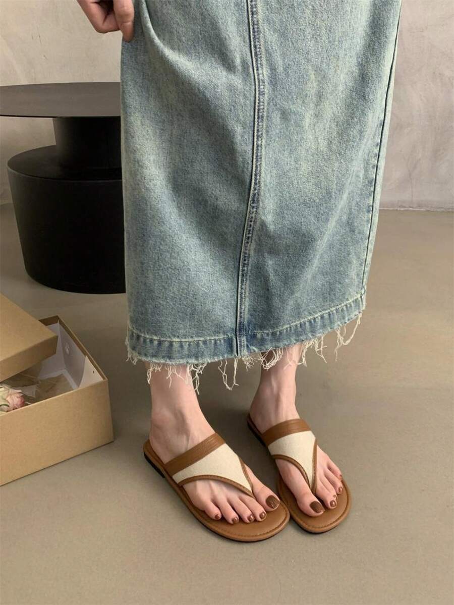 Worn view of two-tone brown and cream flat thong slide sandals with denim skirt for casual walking