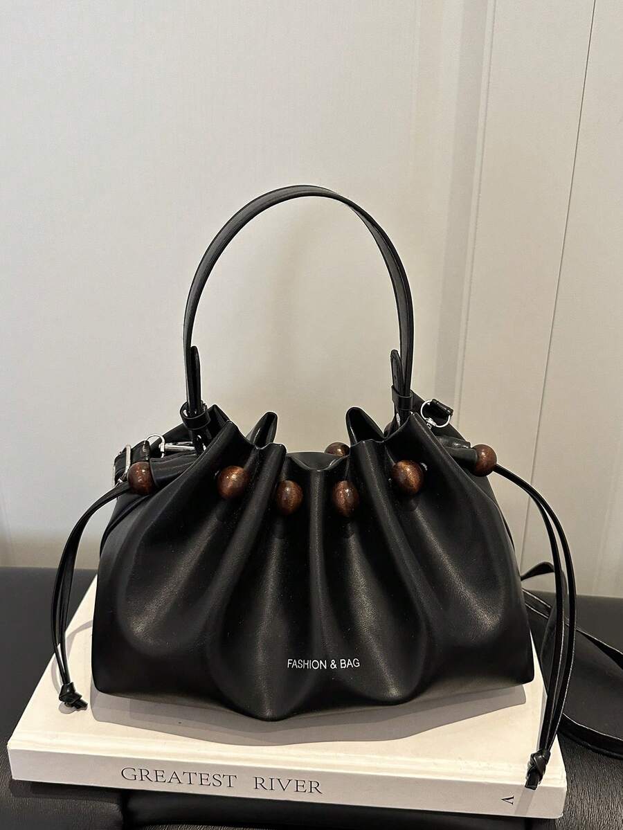 Detail view of black ruched bucket bag with wood beads and silver buckles