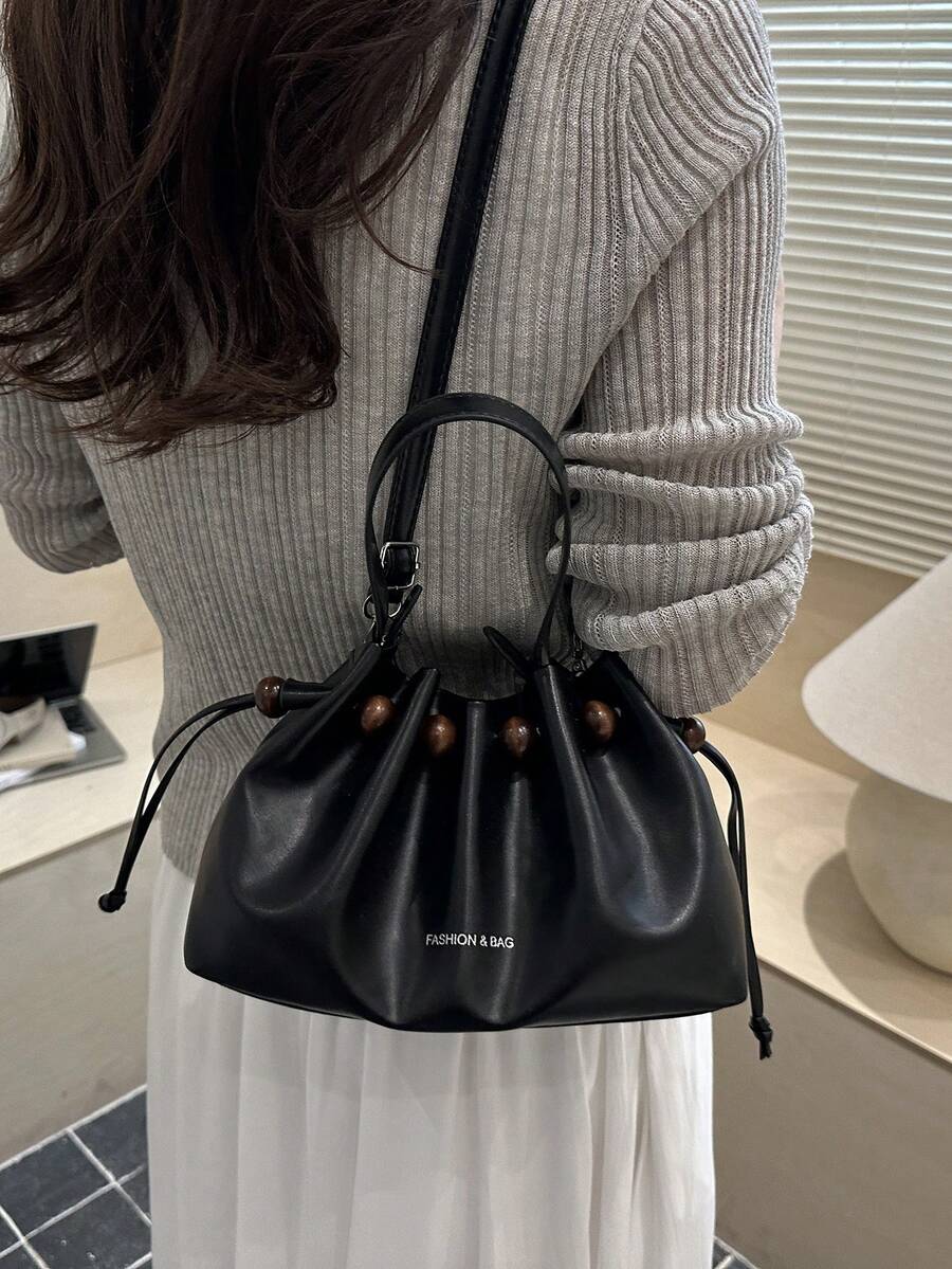 Black glossy faux leather bucket bag showing adjustable shoulder strap