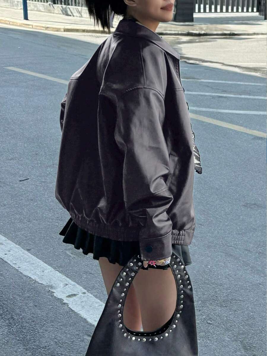 Back three-quarter view of charcoal grey faux leather bomber jacket outdoors