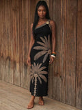 Front view of black palm print one-shoulder maxi dress with gold floral shoulder accent