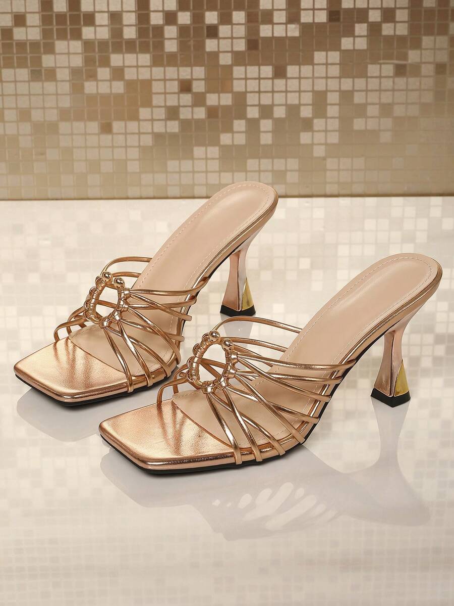 Front product view of champagne metallic slip-on sandals with wrapped rings and sculpted heels