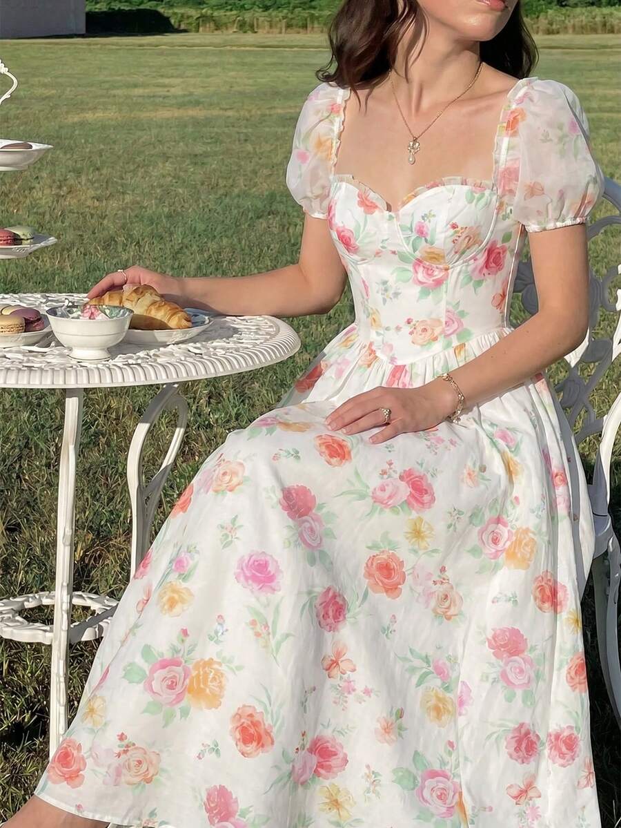 Front three-quarter view of white floral sweetheart midi dress with sheer puff sleeves in a garden
