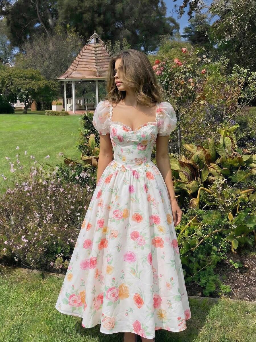 Front three-quarter view of white floral sweetheart midi dress with sheer puff sleeves in a garden