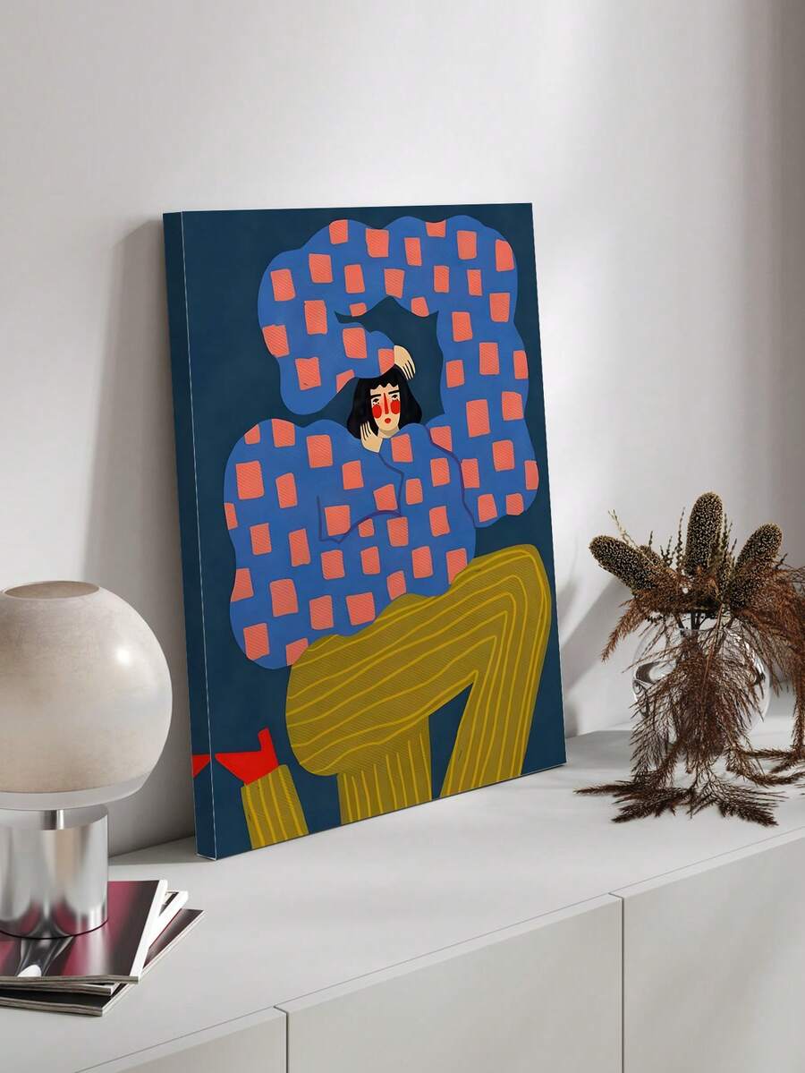 Abstract seated human figure canvas art in wood frame beside a woven chair
