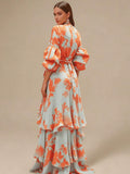 Rear three-quarter view of coral botanical maxi dress showing sash knot and layered skirt