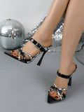 Elevated front view of black and white buckle high-heel sandals worn indoors