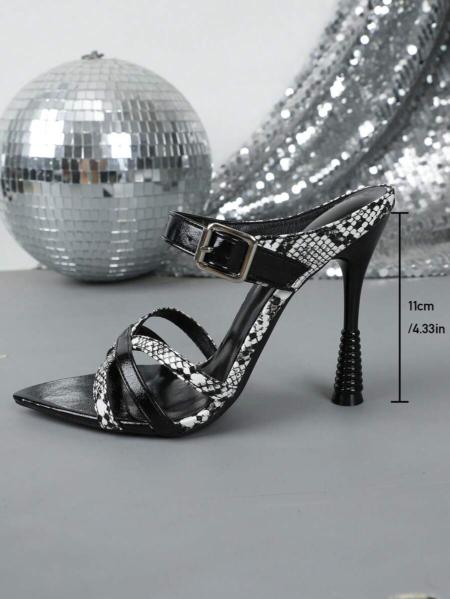 Three-quarter view of black and white pointed-toe stiletto sandals on a disco set