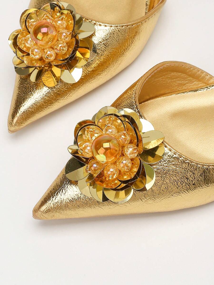 Close-up toe view of gold metallic flats with amber beads and crystal flower details