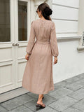 Rear street view of brown striped A-line maxi dress with bishop sleeves and back buttons