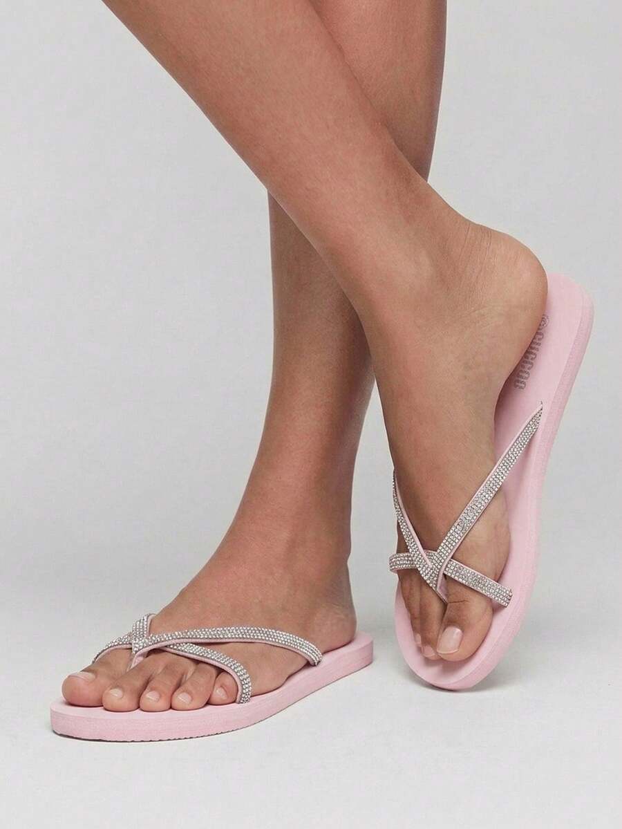 On-foot front view of pink jeweled flip flops with crossed legs
