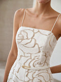 Close-up of white rose appliqué jumpsuit fitted bodice and gold-tone buckle belt
