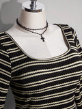 Close-up of square neckline and narrow cream stripes on black knit dress