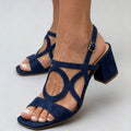 Three-quarter view of navy blue open toe buckle strap block heel sandals on model