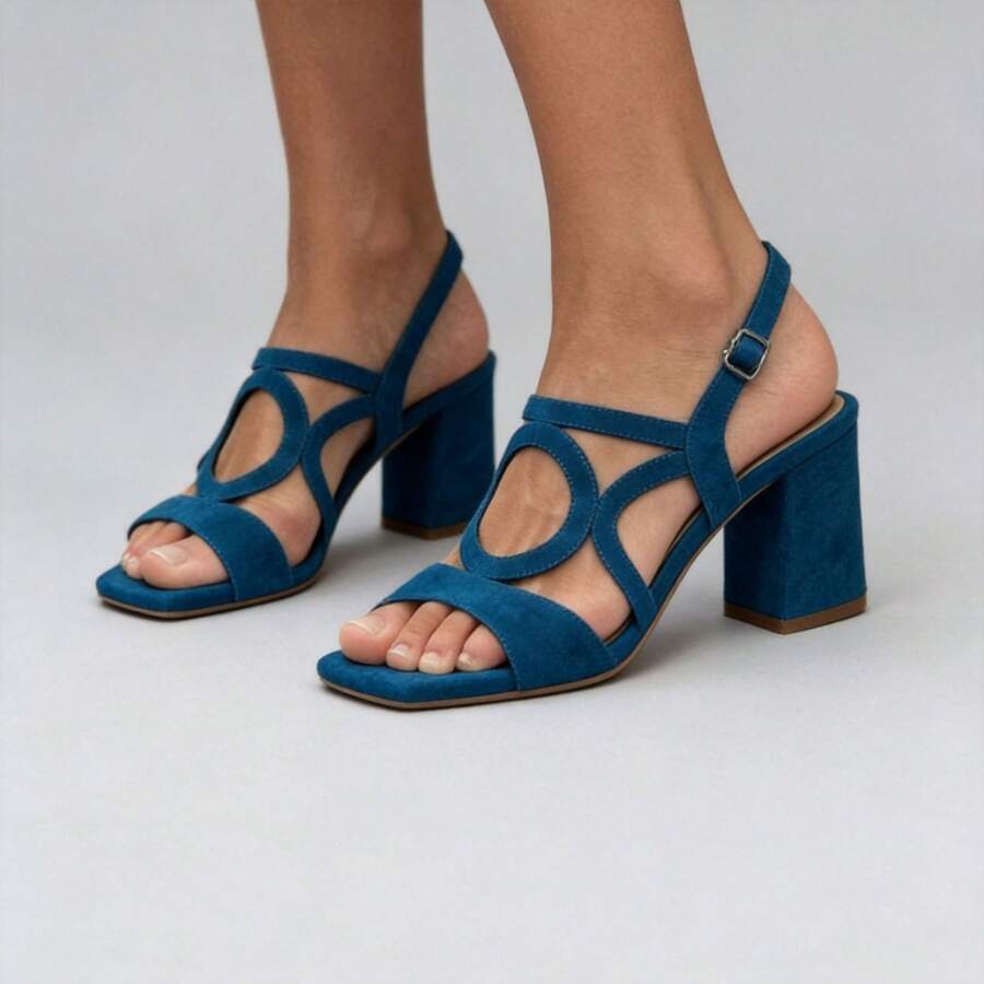 Three-quarter view of deep teal criss-cross buckle block heel sandals on model