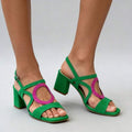 Three-quarter view of green and rose red round buckle block heel sandals on model