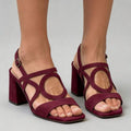 Three-quarter view of burgundy open toe strappy block heel sandals on model