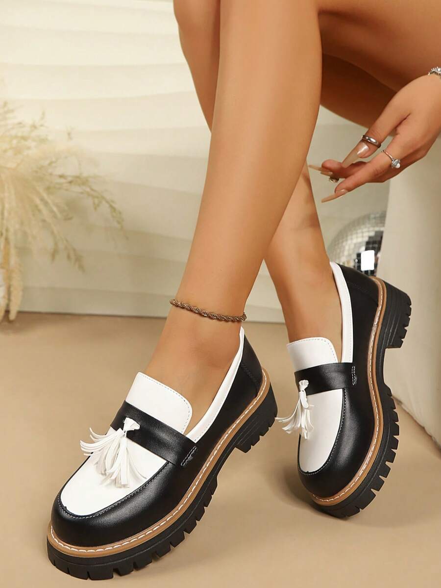 Top-side view of black and white tassel loafer with rounded toe, brown welt, and thick lug sole