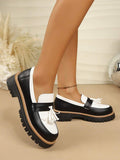 Side and outsole view of black and white tassel loafers with thick black lug soles
