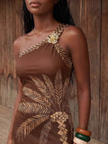 Close view of brown palm print maxi dress with gold floral shoulder accent
