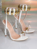 Close-up display of white and gold high stiletto sandals with metallic arch ankle strap