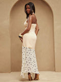 Back view of ivory halter maxi dress with open back, fitted seamed waist and dotted asymmetric skirt