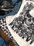 Close-up of white graphic T-shirt showing black skull, roses, and distressed text artwork