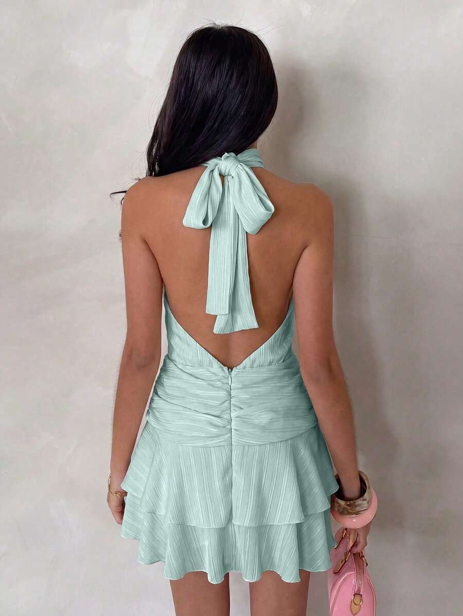 Back view of mint green halter mini dress with tied neck and open V back