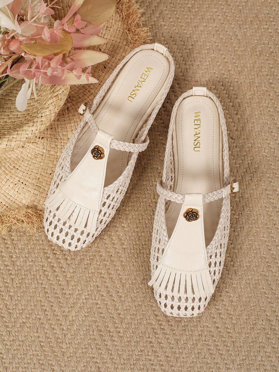 Overhead pair of ivory woven women’s flats with gold floral ornaments and tassel fringe