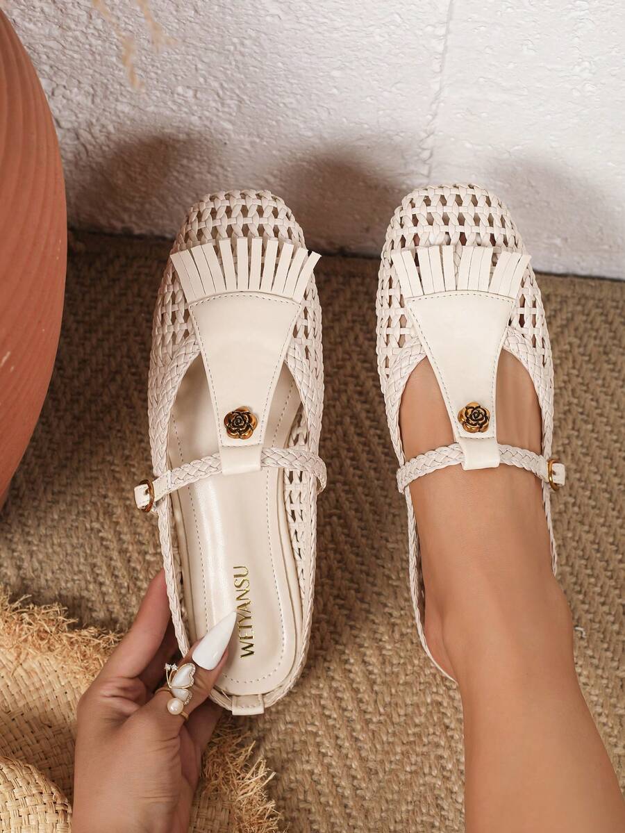 Angled overhead view of ivory woven Mary Jane flats with floral T-straps and fringe