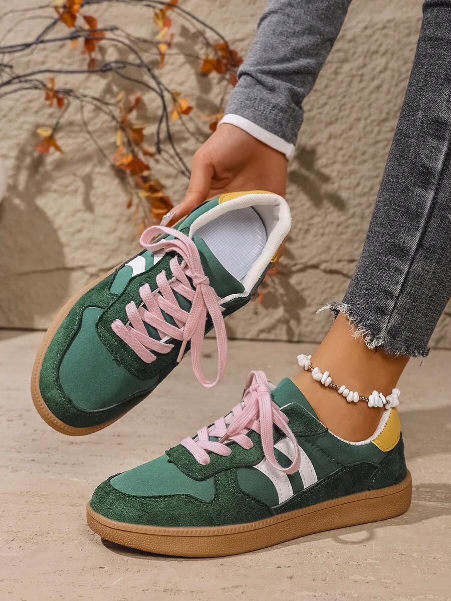Overhead side view of green retro sneakers with white stripes and bright pink laces