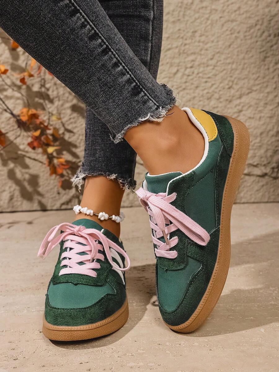 Front-side view of green low-top sneakers with white stripes, pink laces, and round toes