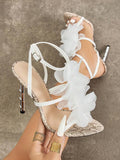 Handheld close-up of white and beige 3D floral cross-strap square-toe stiletto sandals with metallic heel