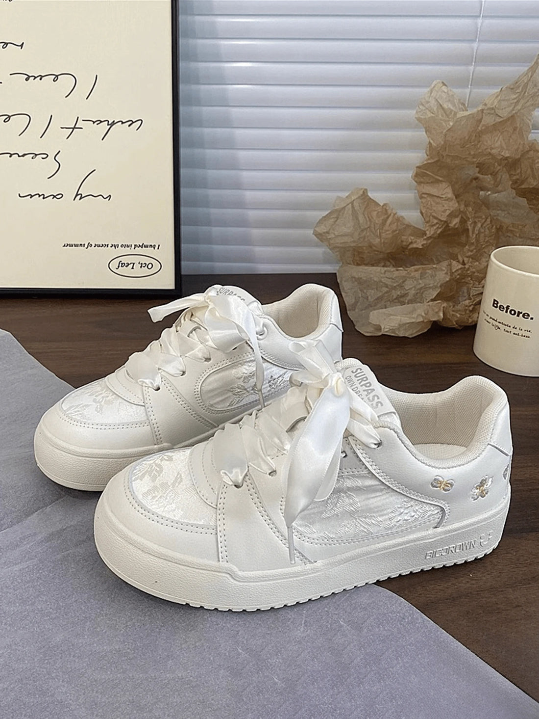 Top-front view of white platform sneakers with satin ribbon laces and floral embroidery