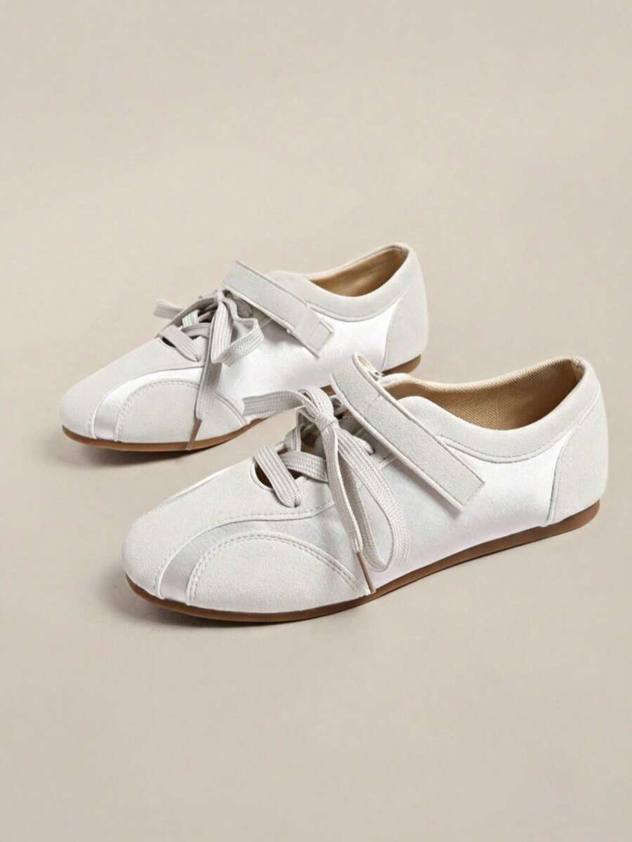Pair of white low-top sneakers with laces, hook-and-loop straps, and flat brown gum soles