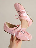 Hand-held front-top view of pale pink lace-up sneakers with hook-and-loop instep straps