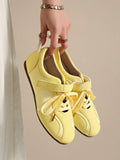 Suspended front view of pale yellow rounded-toe strap sneakers with brown gum soles
