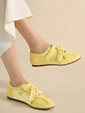 Side view of pale yellow strap sneakers worn against a beige studio backdrop