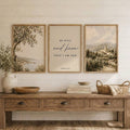Three-piece scripture wall-art set with olive tree, ‘Be still and know that I am God’ verse panel, and village landscape above a console