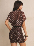 Rear view of brown dotted mini dress showing loose batwing overlay and gathered fitted skirt