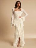 Full front view of an ivory square-neck lace maxi dress with hand on hip and an asymmetric cascading ruffle skirt
